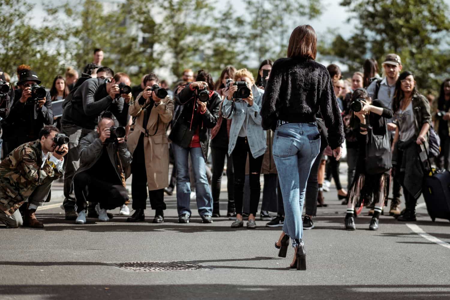 Woman walking towards a group of photographers during London Fashion Week.