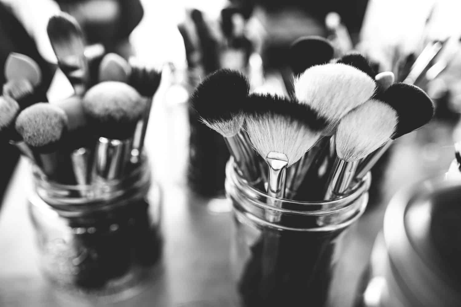 Black and white image of make up brushes on a table.