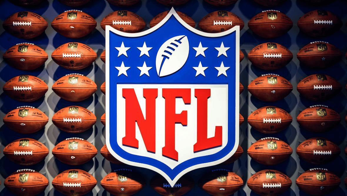 NFL logo in front of a wall of American Footballs