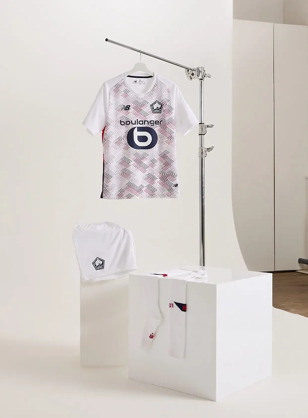 New Balance t-shirt on hanger with shorts and socks displayed underneath in front of white background.