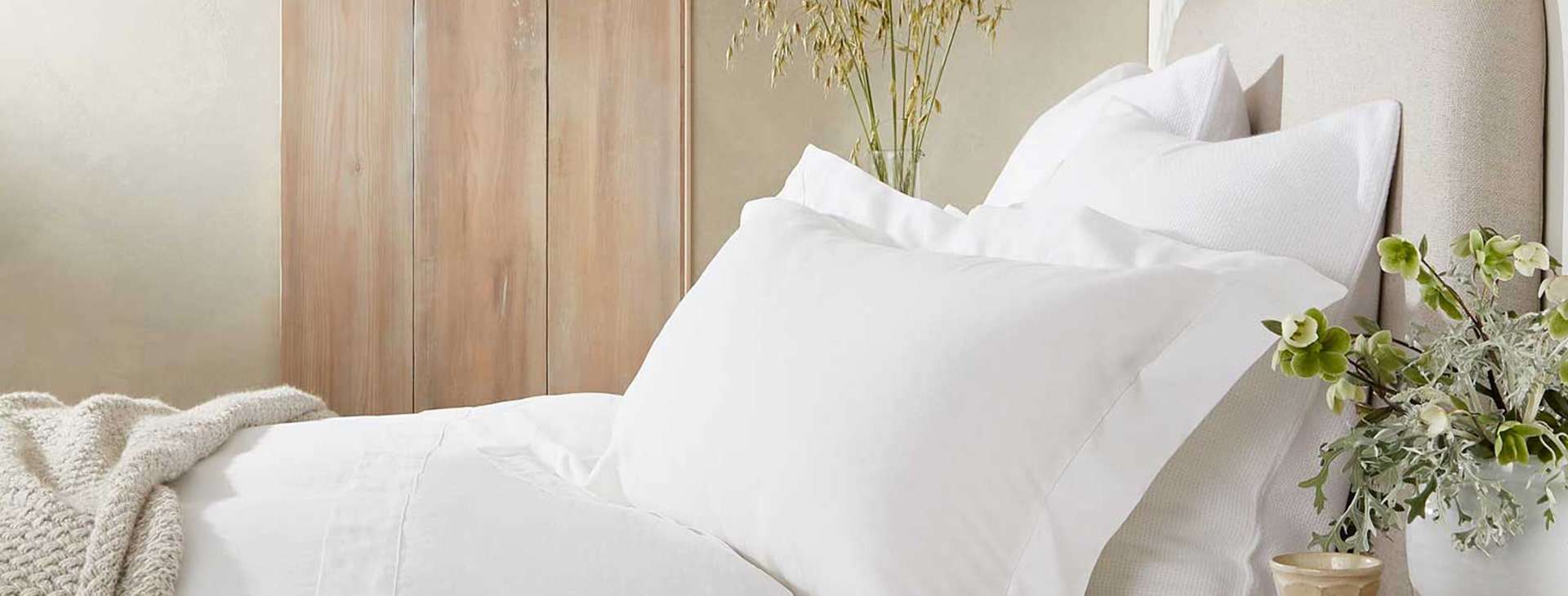 Bed with white bedding and green plants.