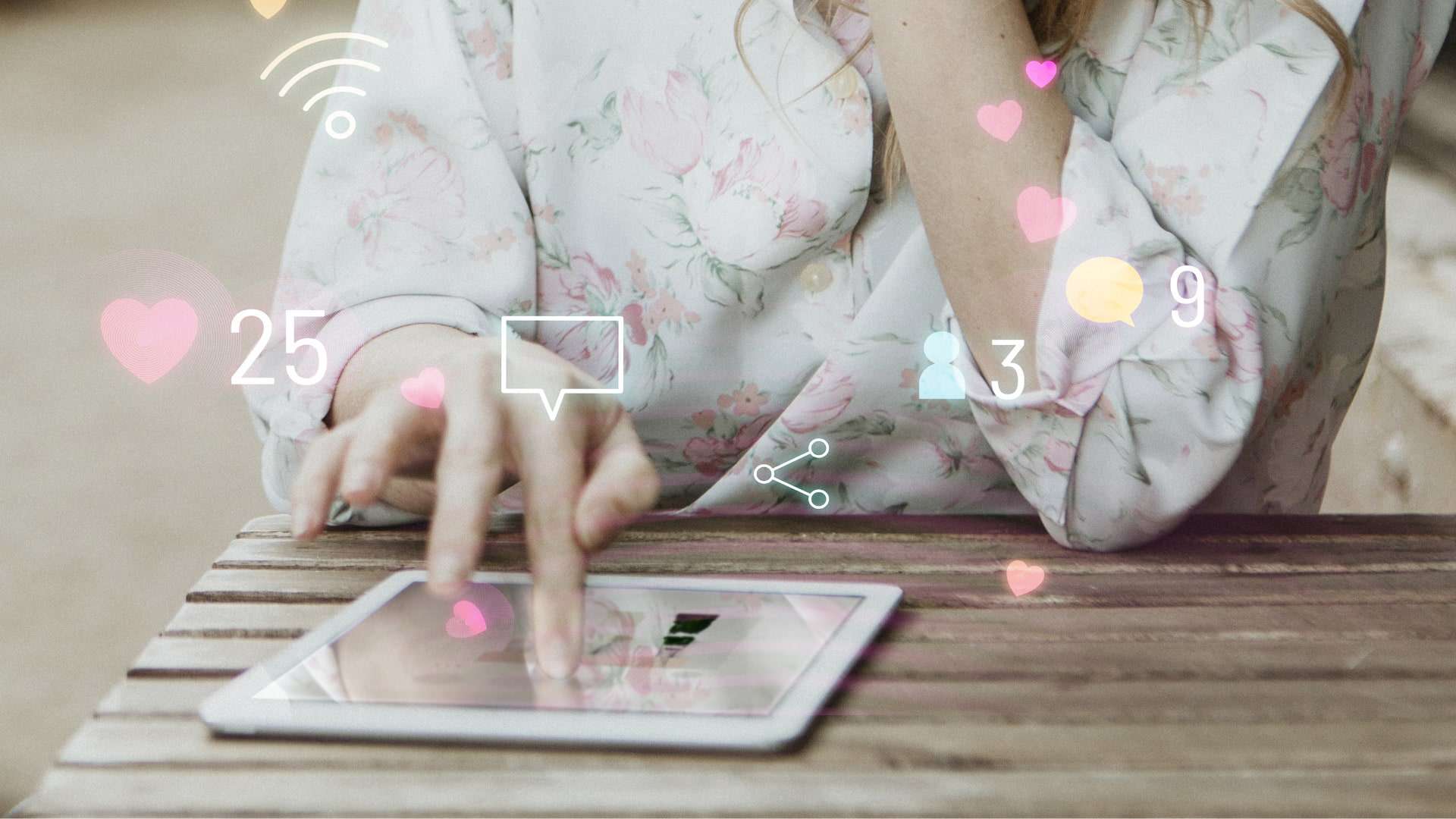 Person wearing flowery blouse sat on picnic bench using a tablet device.