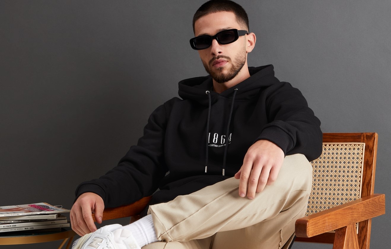 Seated male model wearing WXM hoodie.