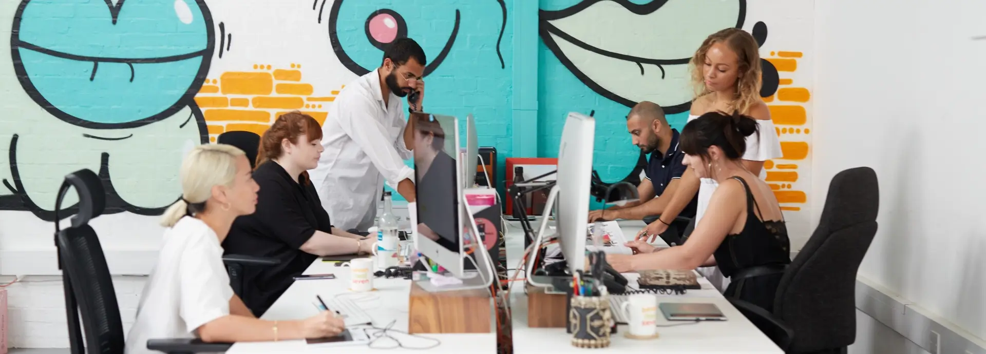 Members of Seventy7 staff working at desks in office.