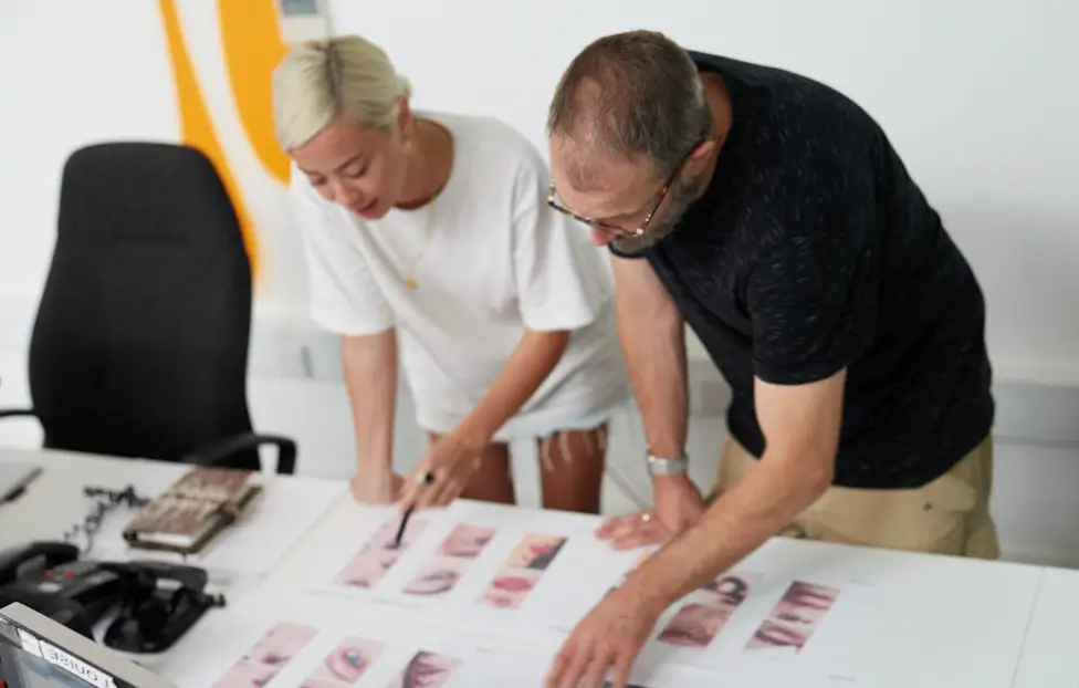 Two members of Seventy7 Staff looking over work on desk.