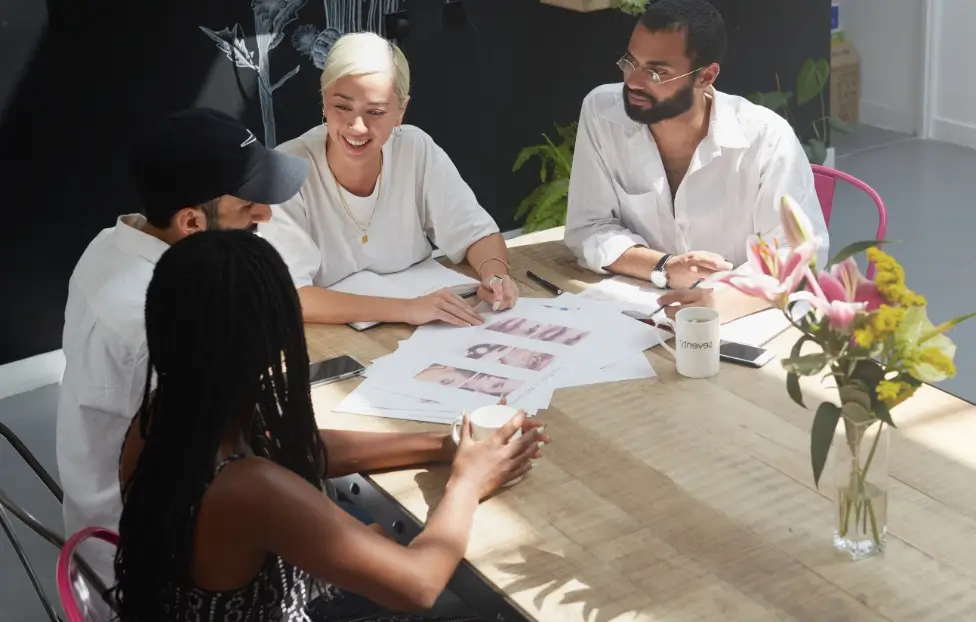 4 members of Seventy7 team collaborating on work around table.