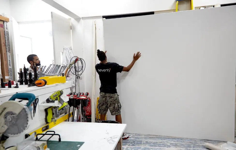 Seventy7 set builders holding large white board.