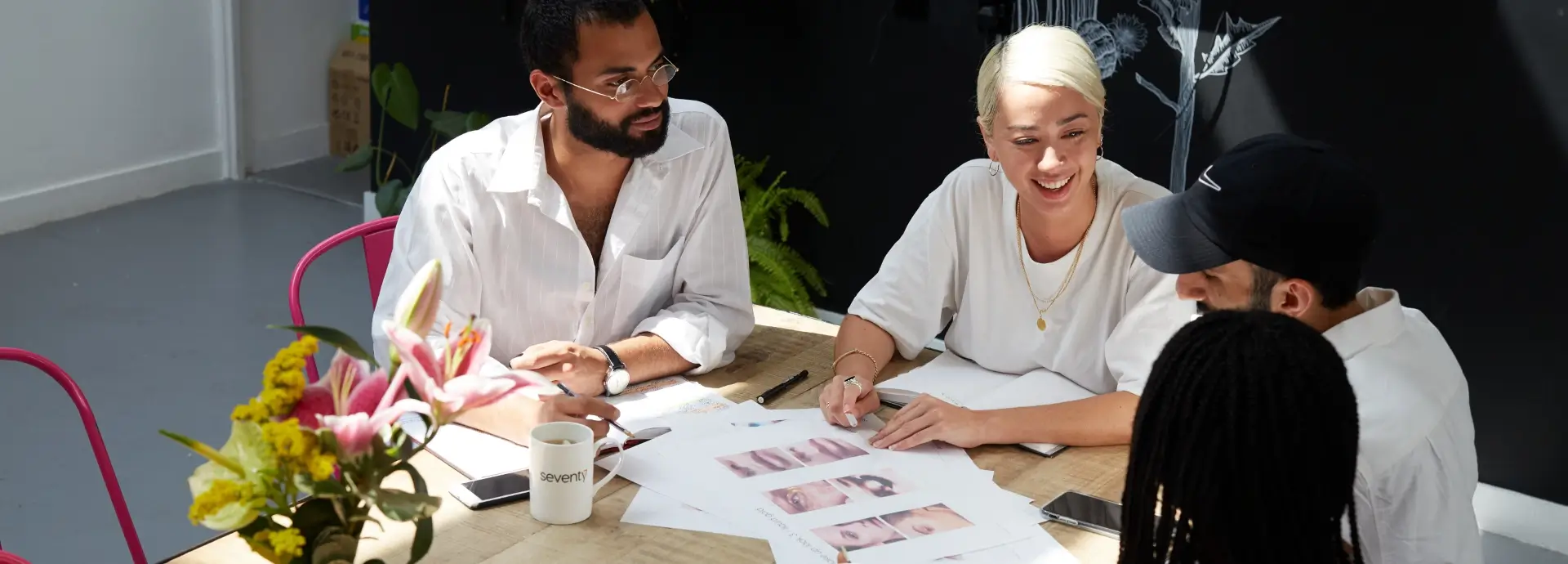 Members of Seventy7 team collaborating on work around table.