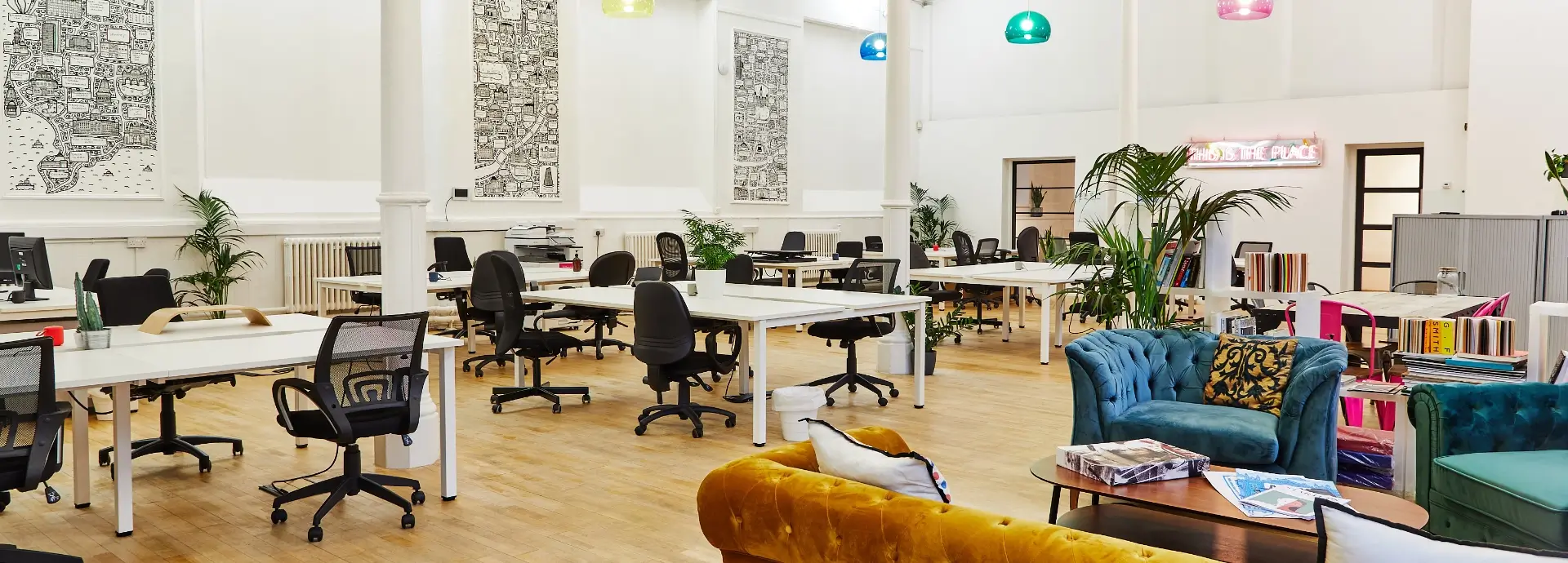 Seventy7 Manchester office with desk, chairs and seating area with doodle style landscape artwork on the back wall.