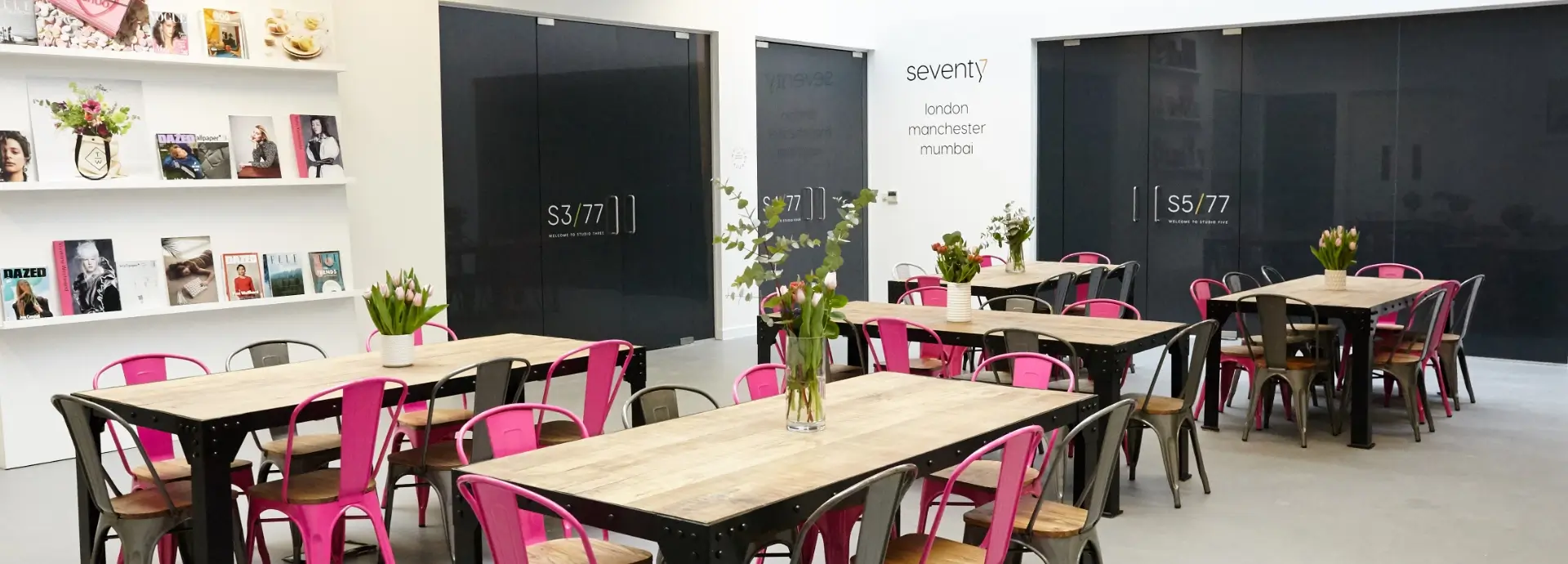 Wide shot of Seventy7 London communal area with tables and chairs.