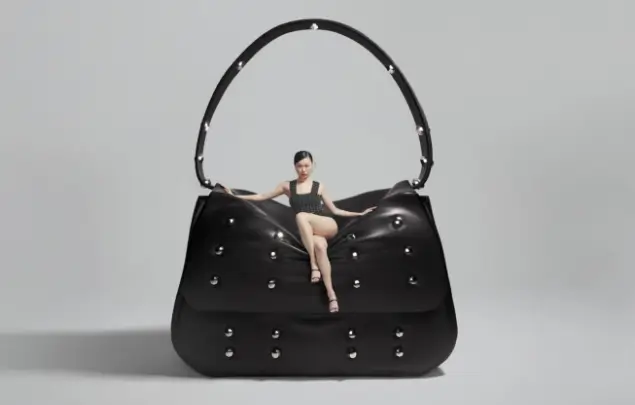 Lady sat on top of oversized black handbag.