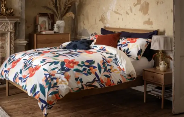 Beige bedroom set up with flowery orange and navy blue bedding.