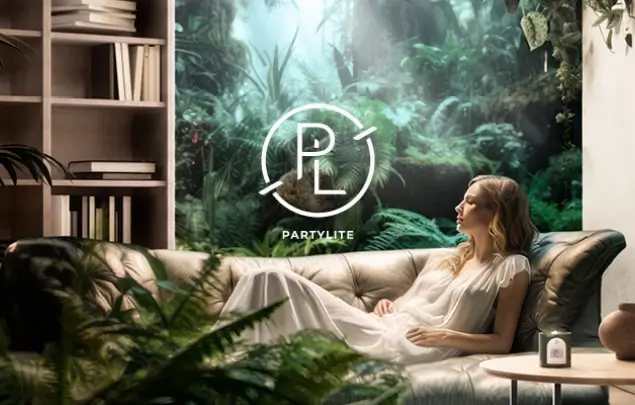 Women in white dress laying on sofa in front of leafy wallpaper with PartyLite logo on it.