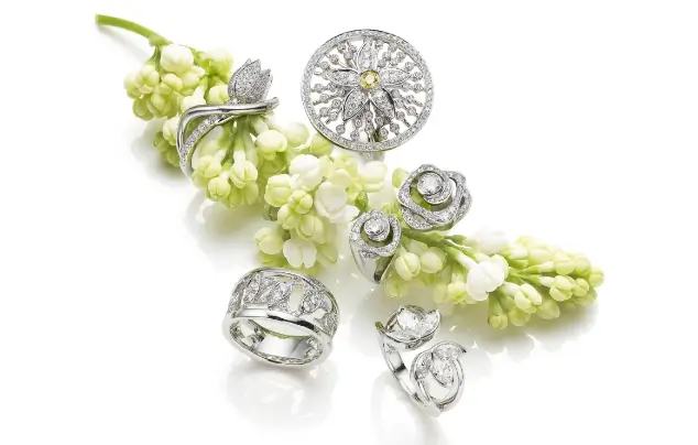 Boodles jewellery with white and green flowers on white background.