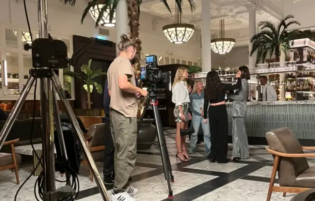 Behind the scenes shot with 3 models, a make up artist and a photographer in a bar.