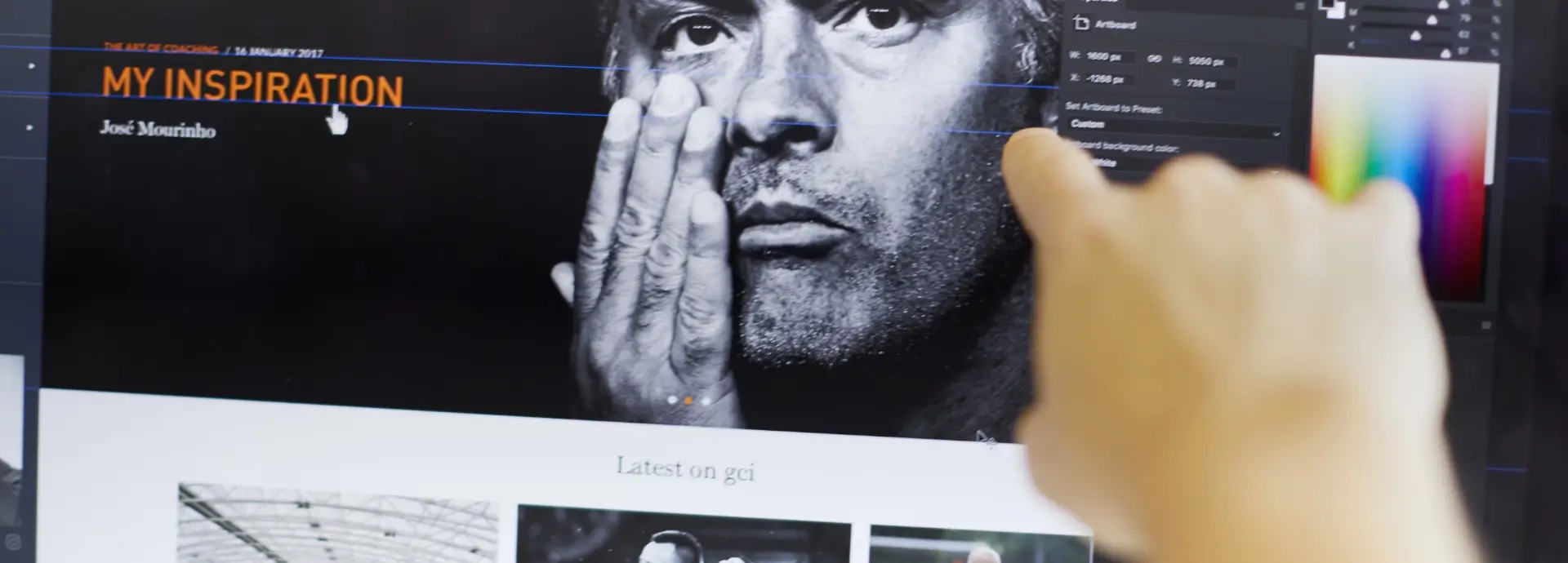 Hand pointing at a screen with website design elements on it.