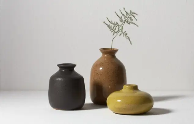 3 decorative pots in shades of brown in front of white background.