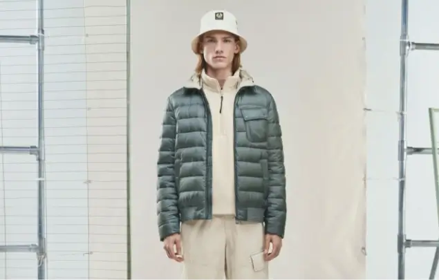 Male model posing wearing beige clothing under green insulated jacket.