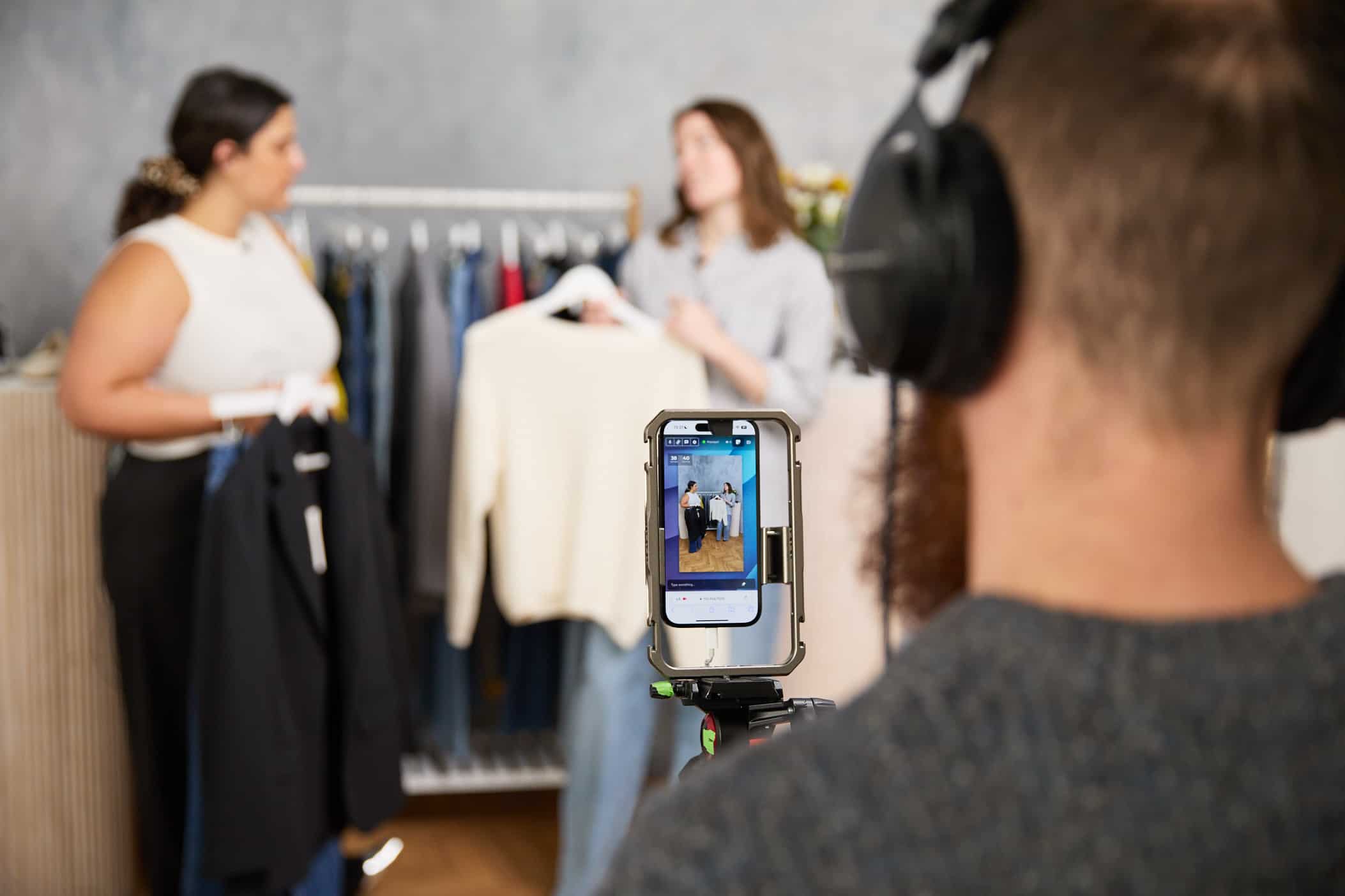 Two presenters being filmed on a mobile phone.