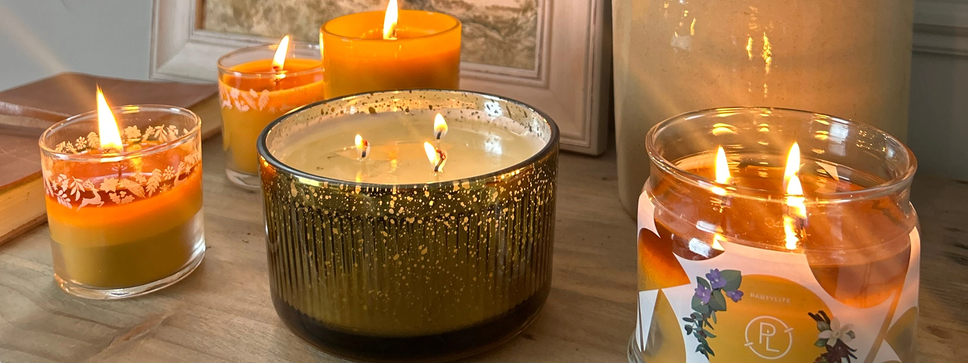 A wooden shelf featuring 5 different sized PartyLite candles.