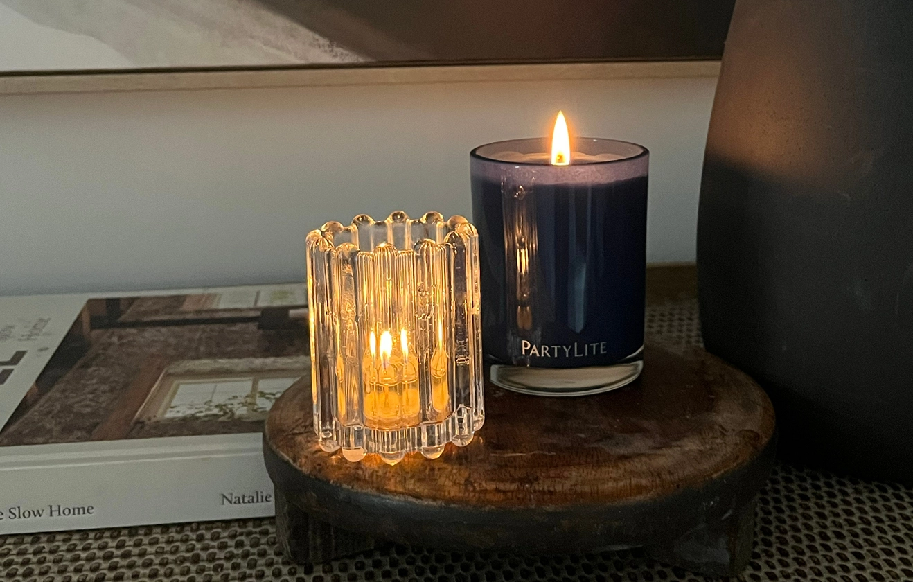 2 PartyLite candles on a sideboard next to a home style book.