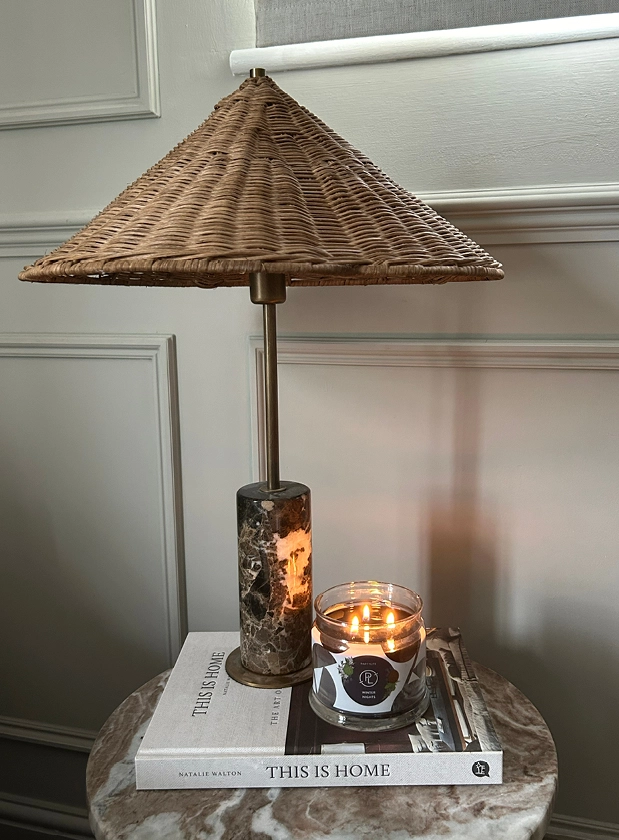 Small side table with lamp and lit PartyLite candle sat on top of a book.