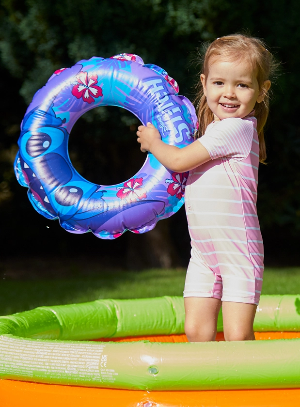 Young girl playing in paddling pool with a Disney inflatable ring.