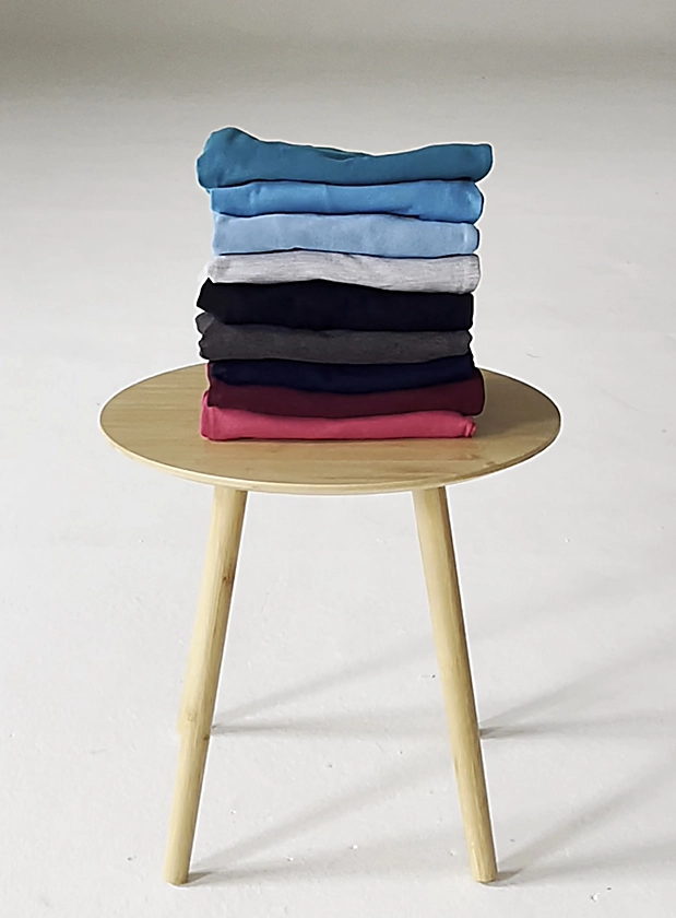 Wooden table with Simon Jersey garments folded and stacked in a pile.